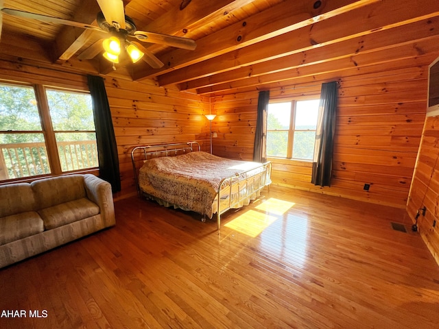 bedroom featuring wood walls, hardwood / wood-style flooring, ceiling fan, wood ceiling, and beam ceiling