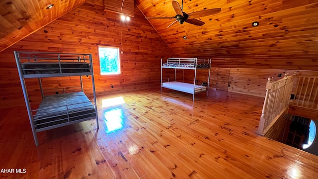 unfurnished bedroom with wood-type flooring, wooden ceiling, vaulted ceiling, and wood walls