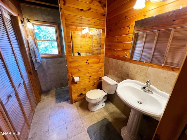 bathroom featuring toilet, sink, and wood walls