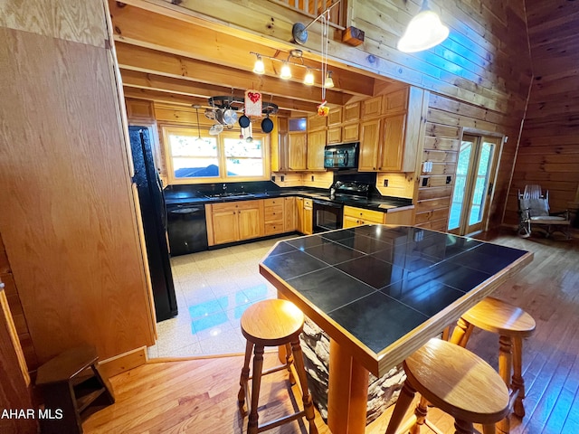 kitchen with beamed ceiling, a healthy amount of sunlight, and black appliances