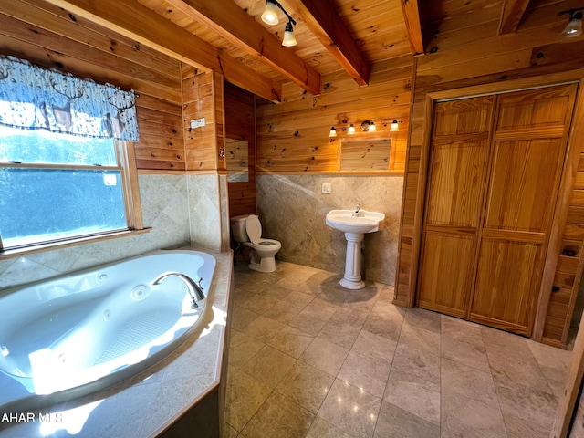 bathroom with wooden walls, beamed ceiling, a bathtub, wood ceiling, and toilet