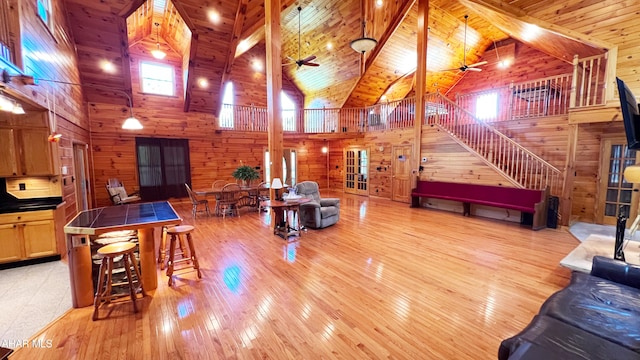 living room featuring wood ceiling, high vaulted ceiling, light hardwood / wood-style flooring, wooden walls, and ceiling fan