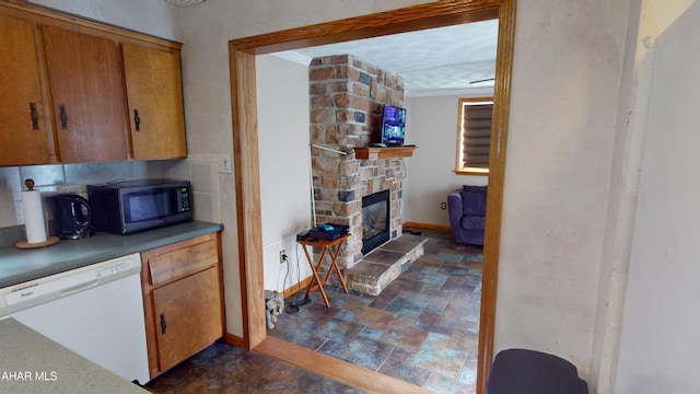 kitchen with a stone fireplace and white dishwasher