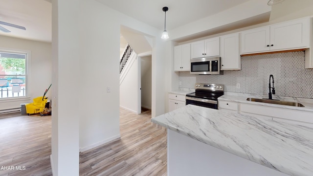 2602 W Chestnut Ave, Altoona, PA 16601 - kitchen with appliances with stainless steel finishes, light wood finished floors, decorative backsplash, and white cabinets