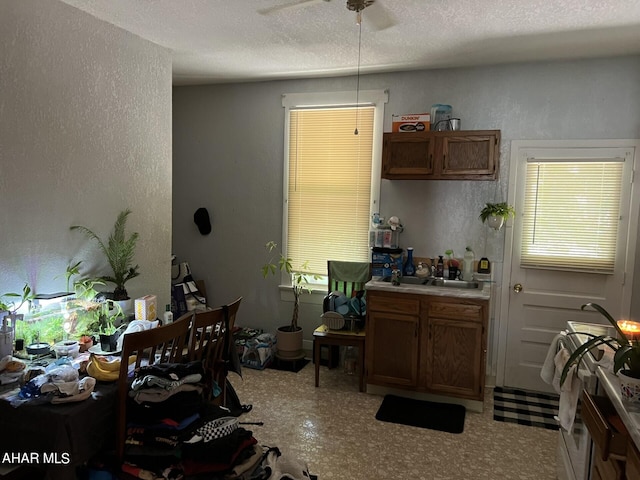 1243 R Main St, Johnstown, PA 15905 - kitchen featuring brown cabinetry, a ceiling fan, a textured ceiling, a textured wall, and light countertops