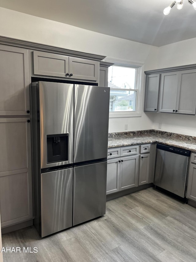 kitchen with light stone counters, stainless steel appliances, gray cabinets, and light hardwood / wood-style flooring