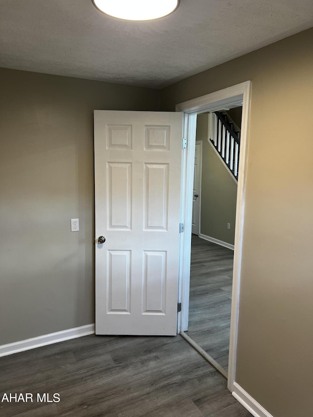 hallway with dark hardwood / wood-style flooring and a textured ceiling