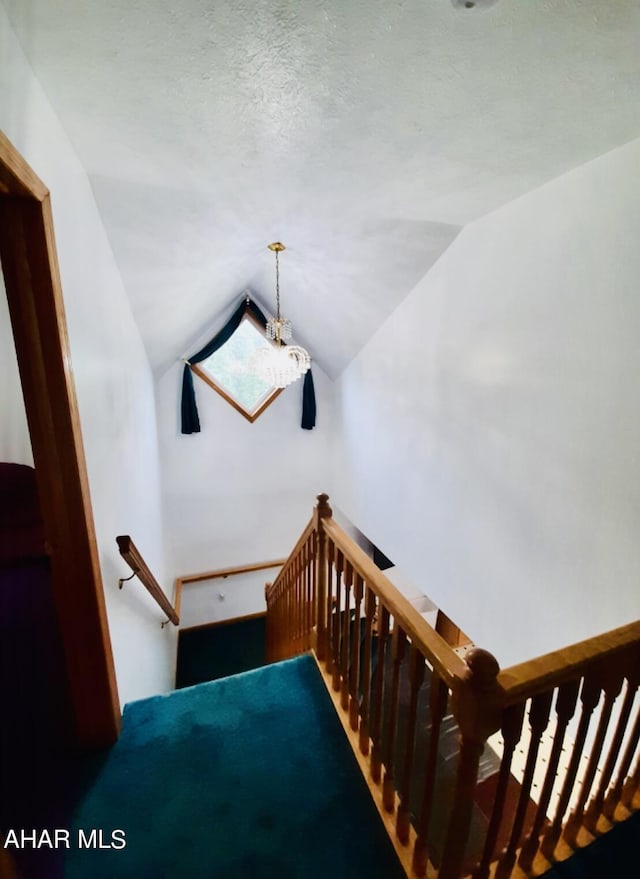 stairway with a textured ceiling and vaulted ceiling