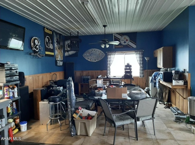 dining area featuring ceiling fan and wooden walls