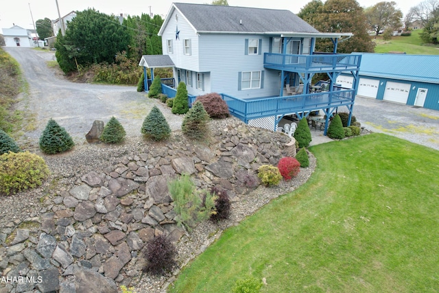 exterior space featuring a lawn, a garage, and a wooden deck