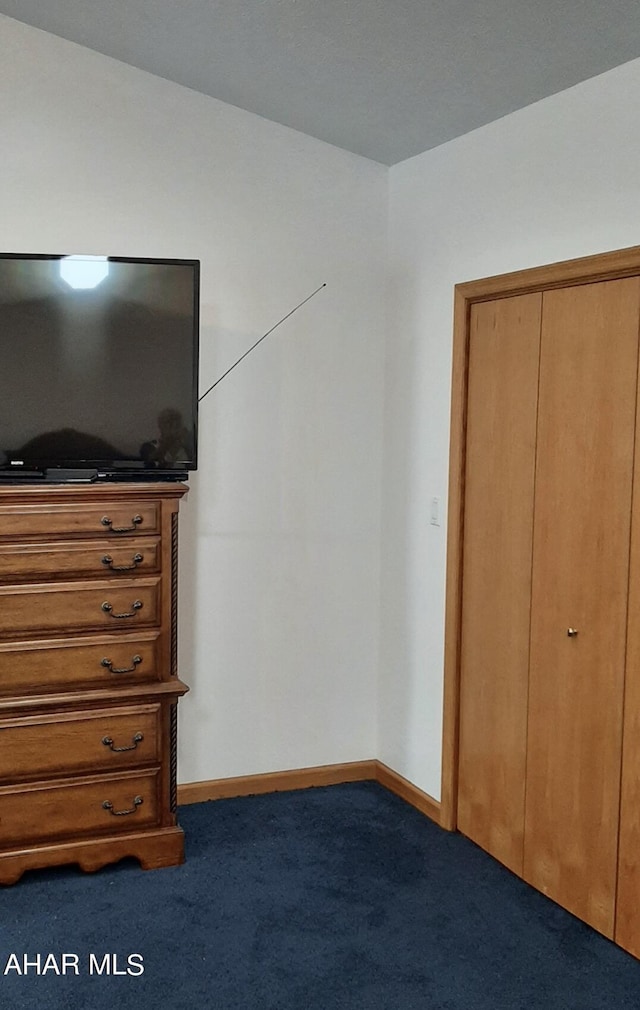 unfurnished bedroom featuring dark colored carpet and a closet