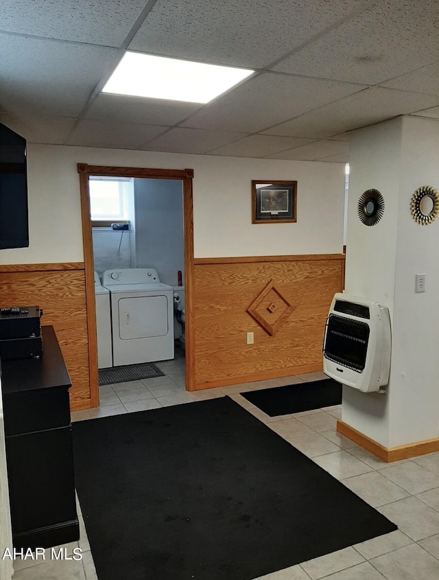 washroom featuring heating unit, wood walls, light tile patterned flooring, and washing machine and dryer