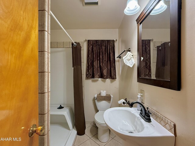 bathroom with toilet, tile patterned flooring, sink, and curtained shower