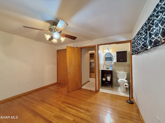 unfurnished bedroom featuring ceiling fan, light hardwood / wood-style flooring, and ensuite bath