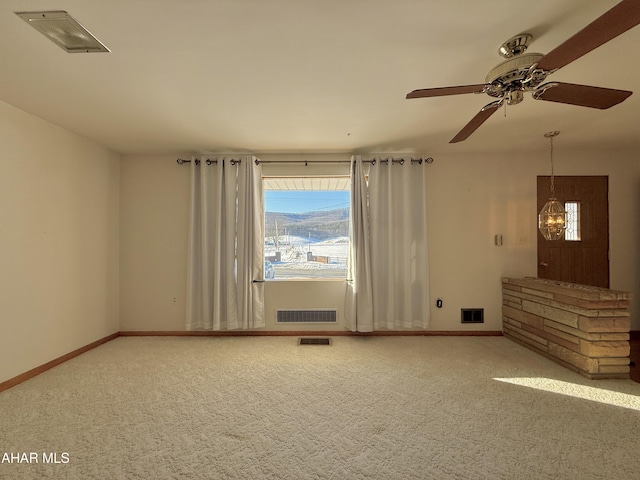 carpeted spare room with ceiling fan with notable chandelier