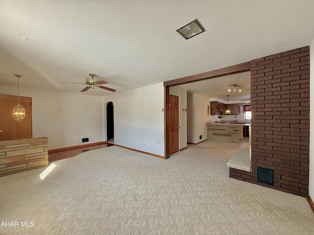 unfurnished living room featuring ceiling fan with notable chandelier and light carpet