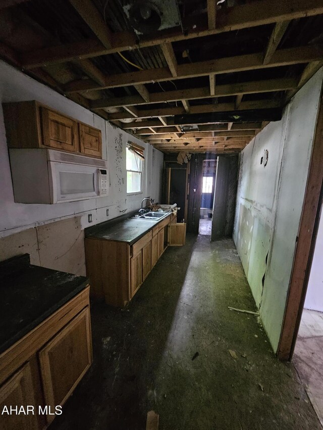 625 N 5th Ave, Altoona, PA 16601 - kitchen with brown cabinets, dark countertops, a sink, and white microwave