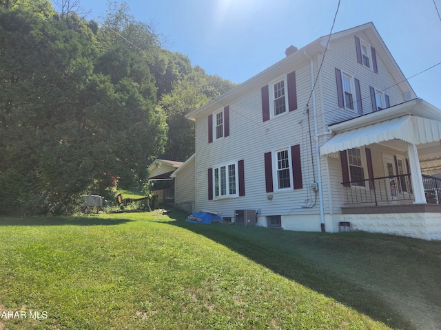 view of property exterior featuring covered porch, central AC, and a lawn