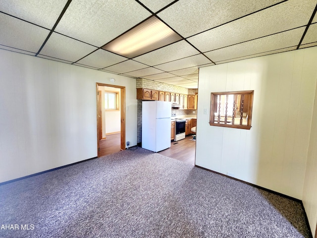 unfurnished living room featuring a paneled ceiling, a wealth of natural light, and carpet floors