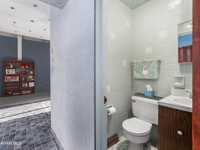 bathroom featuring tile walls, tile patterned flooring, toilet, and vanity