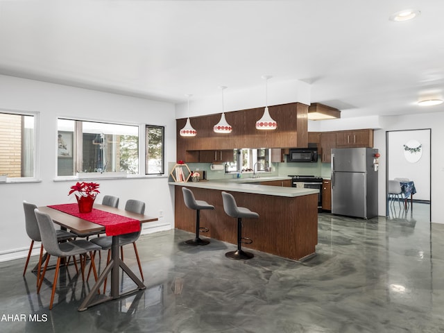 kitchen featuring kitchen peninsula, a kitchen breakfast bar, hanging light fixtures, and appliances with stainless steel finishes