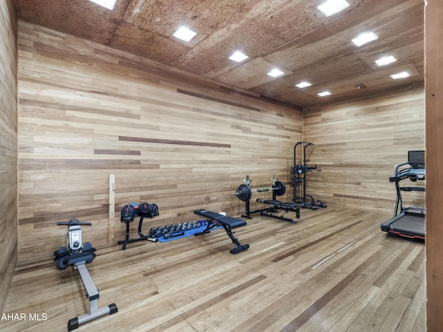 exercise room featuring wood walls and hardwood / wood-style flooring