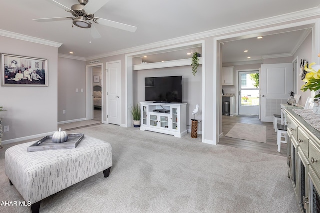 carpeted living room with ceiling fan and ornamental molding