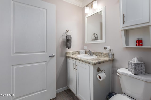 bathroom featuring crown molding, vanity, wood-type flooring, and toilet