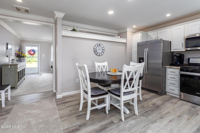 dining space featuring light wood-type flooring and ornamental molding