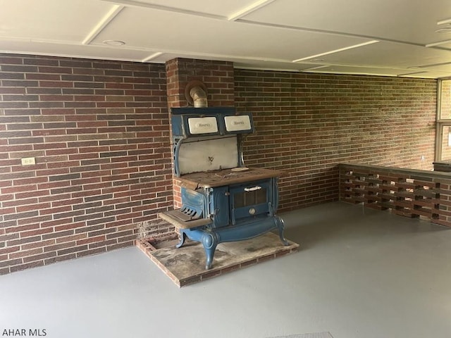 interior space with a wood stove and brick wall