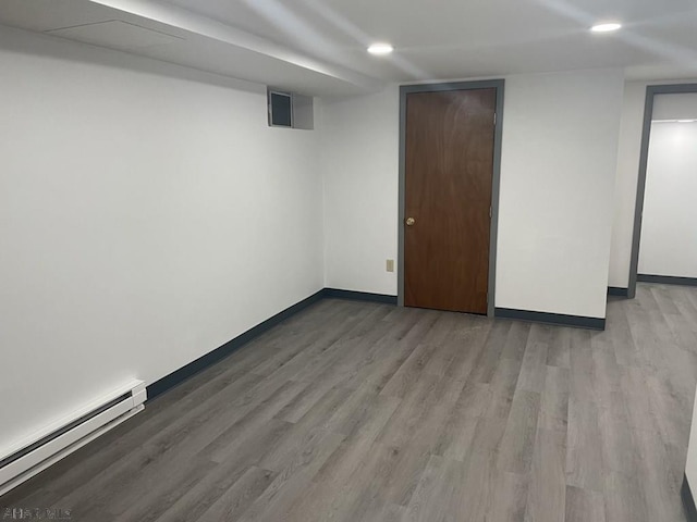 basement featuring a baseboard heating unit and light hardwood / wood-style flooring