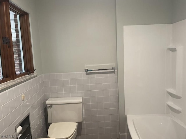 bathroom with tub / shower combination, toilet, and tile walls