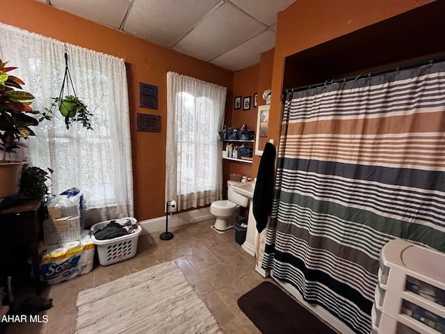 bathroom featuring tile patterned floors, a drop ceiling, and toilet