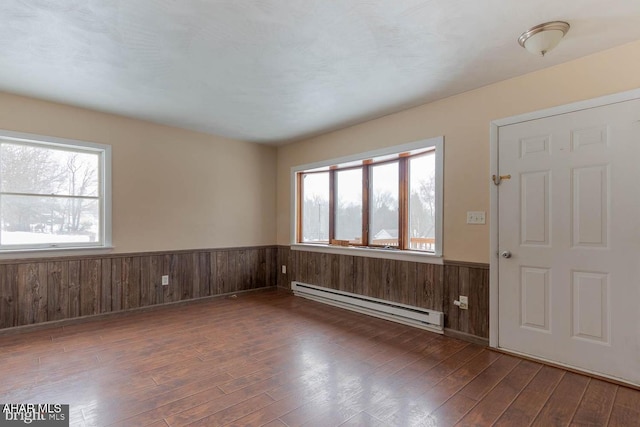 entryway featuring a baseboard heating unit, dark hardwood / wood-style floors, and wood walls