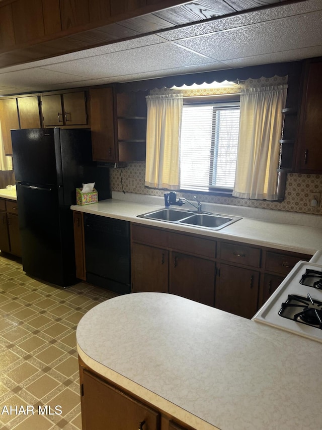 kitchen with black appliances, dark brown cabinetry, decorative backsplash, and sink