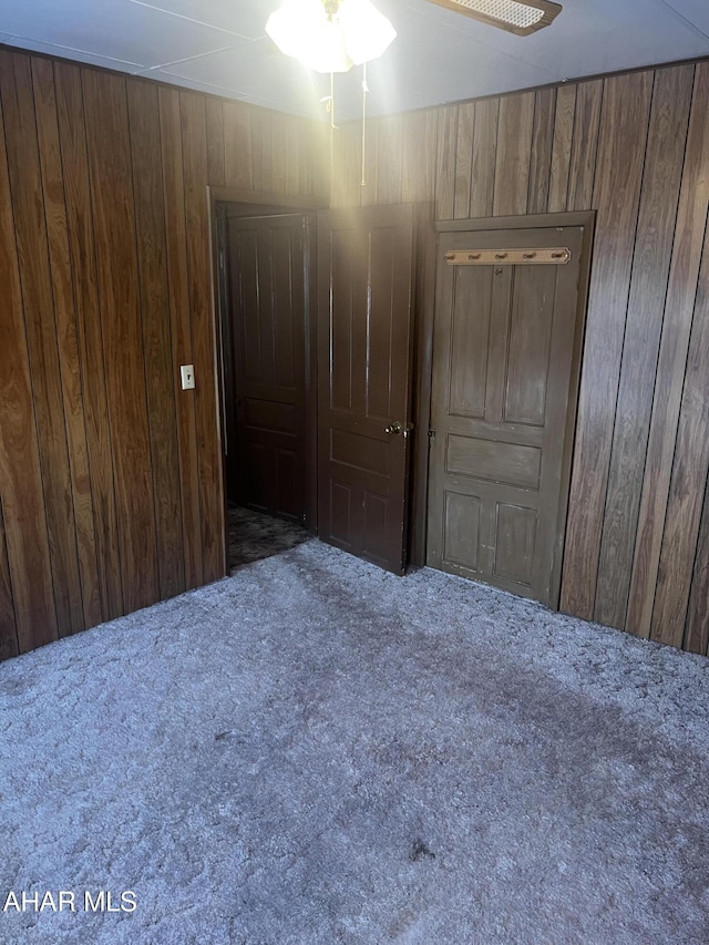 unfurnished room with dark carpet and wooden walls