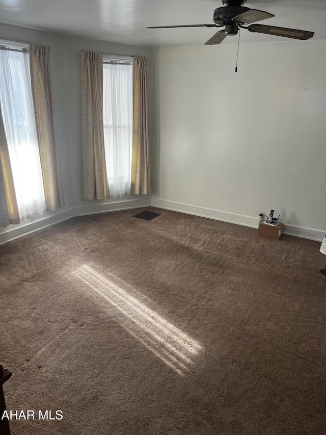 carpeted spare room featuring a healthy amount of sunlight and ceiling fan