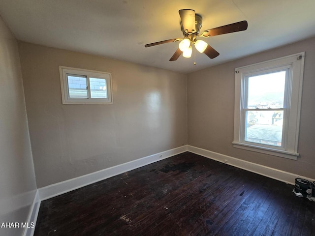 spare room with dark wood-style floors, plenty of natural light, a ceiling fan, and baseboards