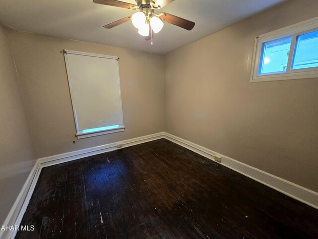 empty room with dark hardwood / wood-style flooring and plenty of natural light