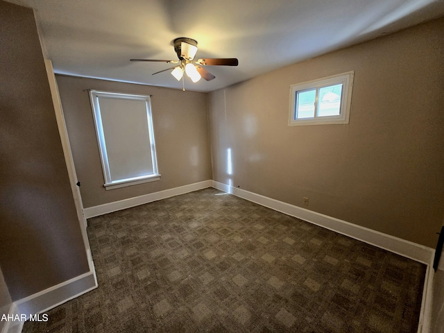 unfurnished room with ceiling fan, baseboards, and dark colored carpet