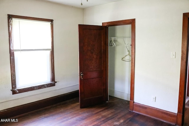 unfurnished bedroom with dark wood-type flooring and a closet