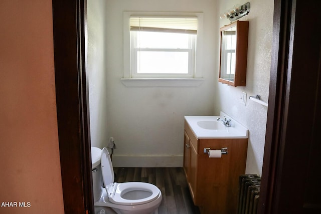 bathroom featuring wood-type flooring, vanity, toilet, and radiator