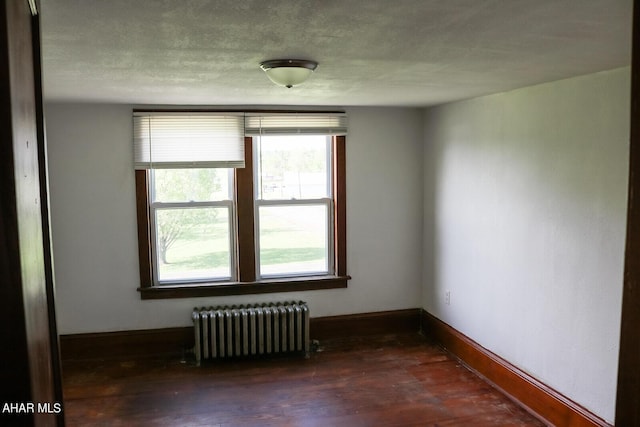 unfurnished room featuring radiator heating unit and dark hardwood / wood-style flooring