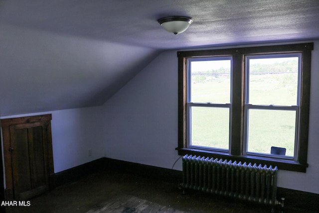 bonus room with lofted ceiling, radiator heating unit, and a textured ceiling