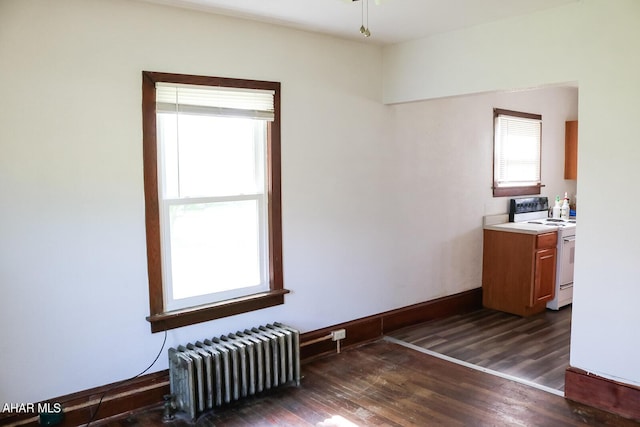 spare room featuring radiator heating unit and dark wood-type flooring