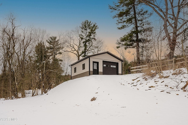 snow covered structure with a garage