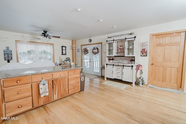 kitchen with ceiling fan, light hardwood / wood-style flooring, and light stone countertops