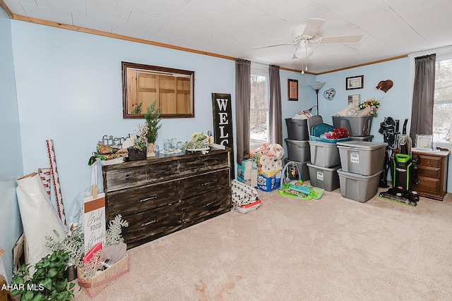 recreation room with ceiling fan, carpet flooring, and ornamental molding