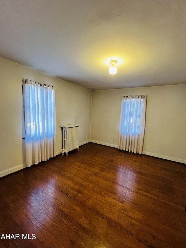 spare room featuring plenty of natural light, dark hardwood / wood-style floors, and radiator heating unit