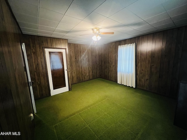 spare room featuring ceiling fan and wood walls